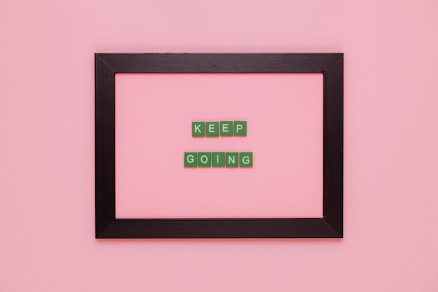 Een roze vlak met een fotoframe erop. Daarin staan de woorden: Keep going.